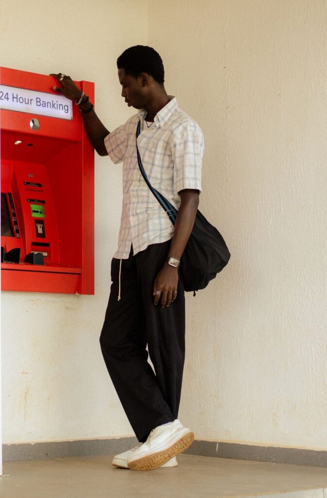 Young man waiting at a red 24-hour banking ATM