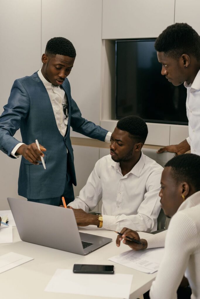 Three men reviewing figures on a laptop in a meeting