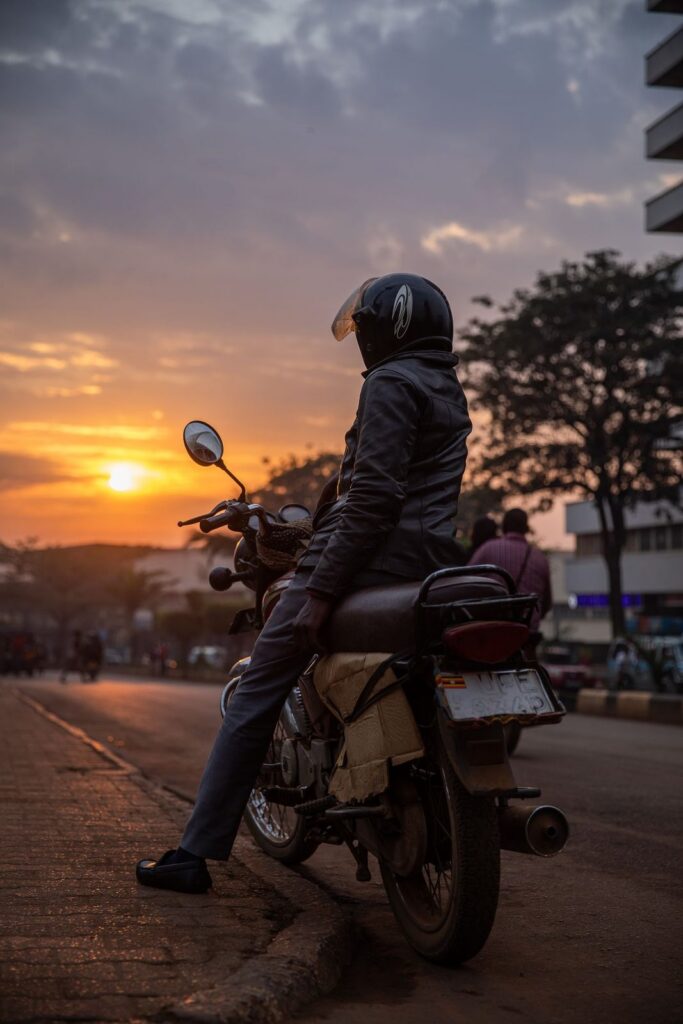 Boda boda rider pausing at sunset on a Kampala road