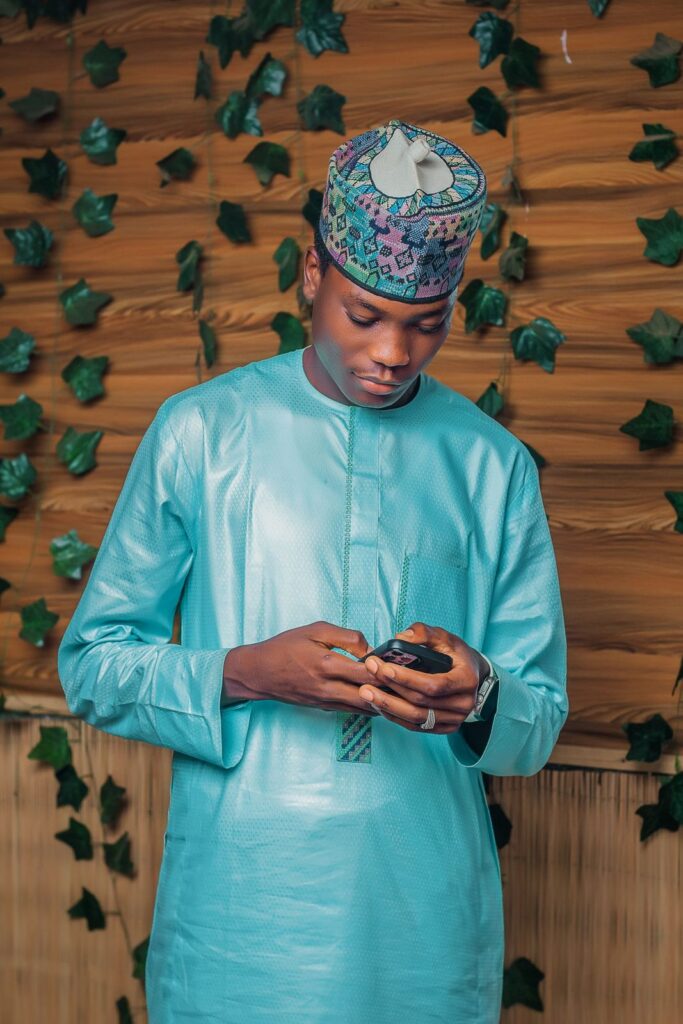 Young man in a blue kanzu checking his mobile phone