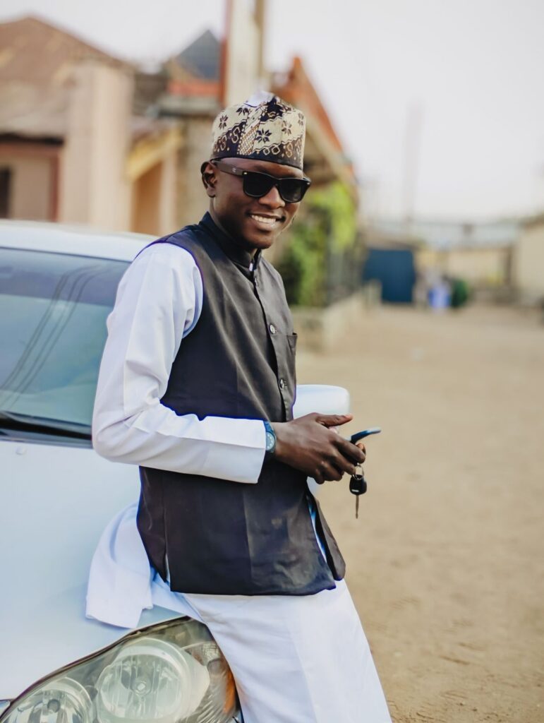 Man in a kanzu leaning on his car with the keys in hand