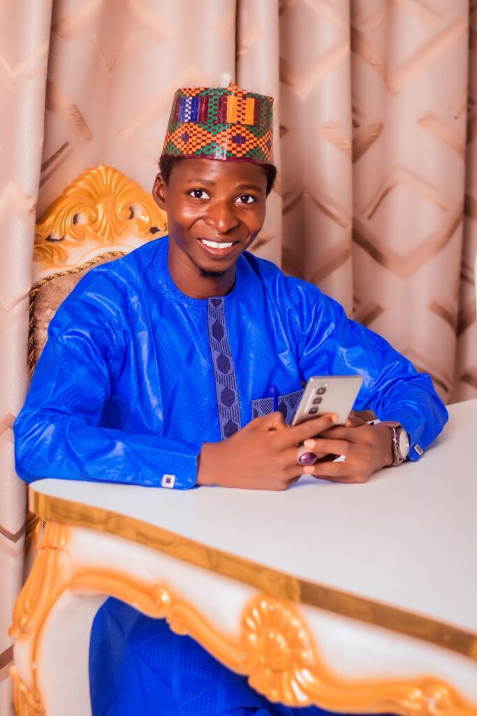 Man in a blue outfit smiling at his smartphone