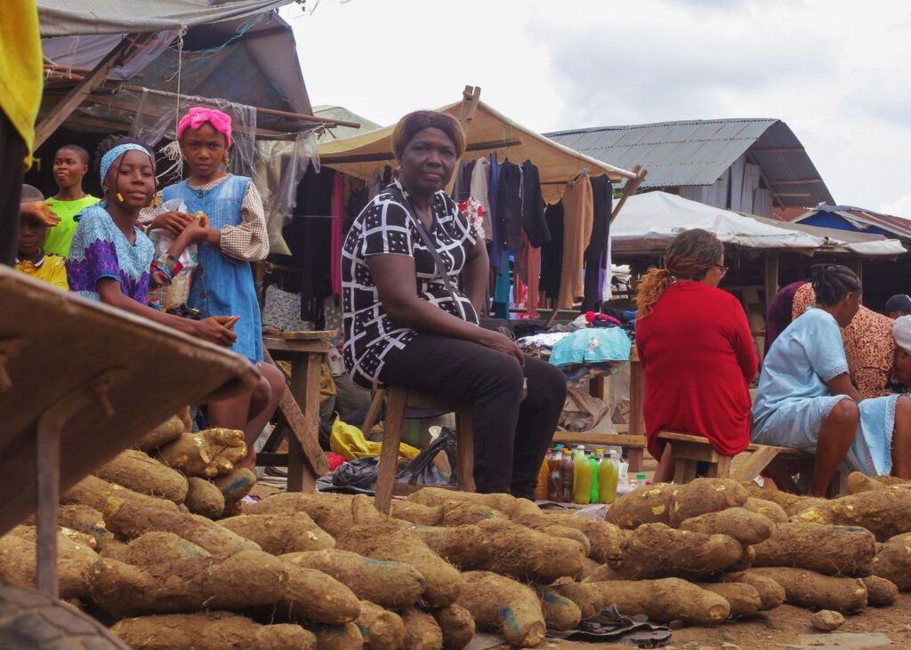 Vendors selling yams and produce at an open-air market