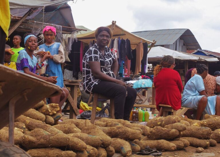 Vendors selling yams and produce at an open-air market