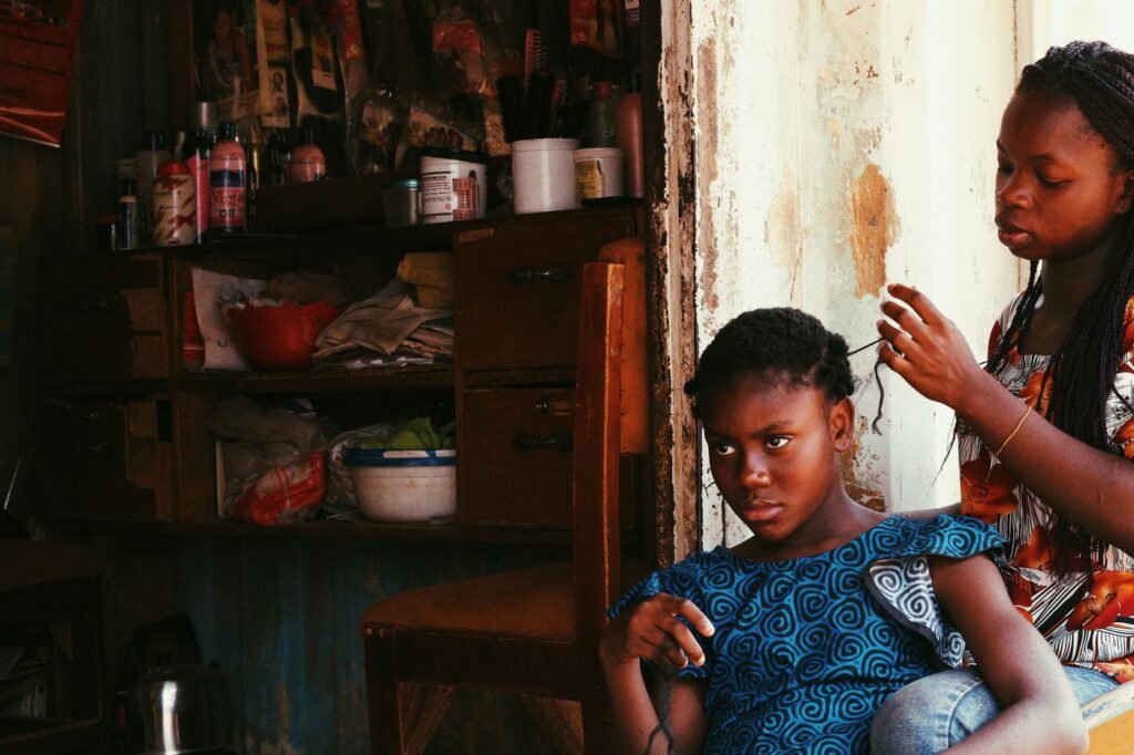 Girl braiding her younger sister’s hair at home