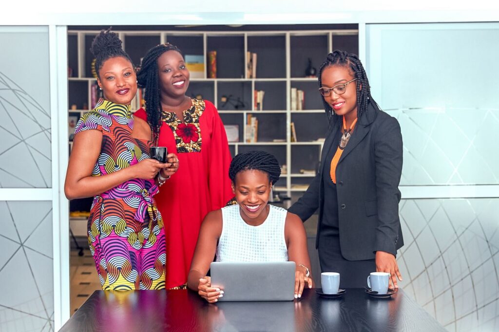 Four professional women around a laptop in an office